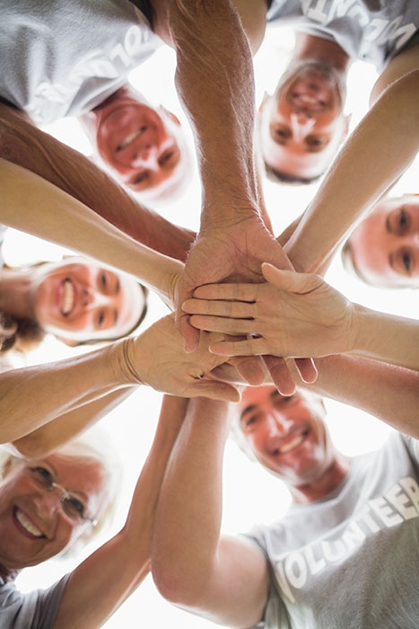 Happy volunteer family putting their hands together